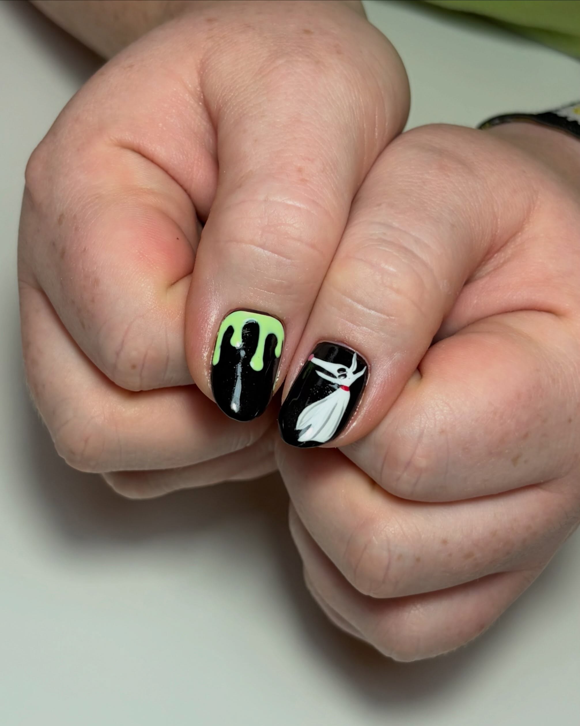 Close-up of a green drip nail and a white ghost character nail